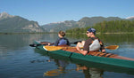 A young couple relaxing during a mountain lake paddle in a Chesapeake Double wooden kayak Thumbnail