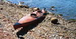 A Chesapeake Double wooden kayak beached on a stony shore Thumbnail