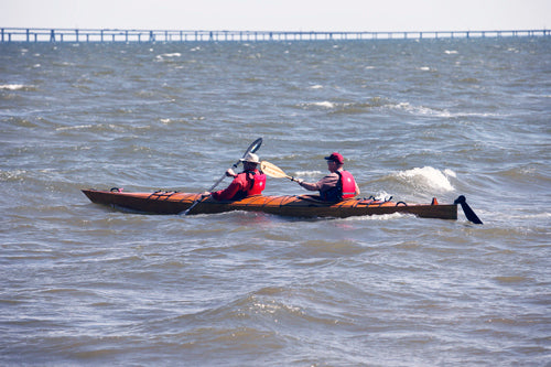 Two paddlers navigating rough water in a Chesapeake Double wooden kayak at OkoumeFest 2010