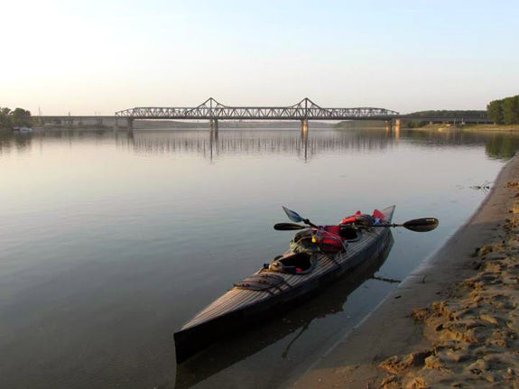 A Chesapeake Double wooden kayak built by Nur K. along the riverbank during an expedition on the Danube River in Romania