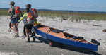 Three paddlers carrying a Chesapeake Triple wooden kayak ashore after a two mile race. Built by Andrew D. Thumbnail