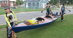 Three paddlers carrying a Chesapeake Triple wooden kayak built by Jason R. Thumbnail