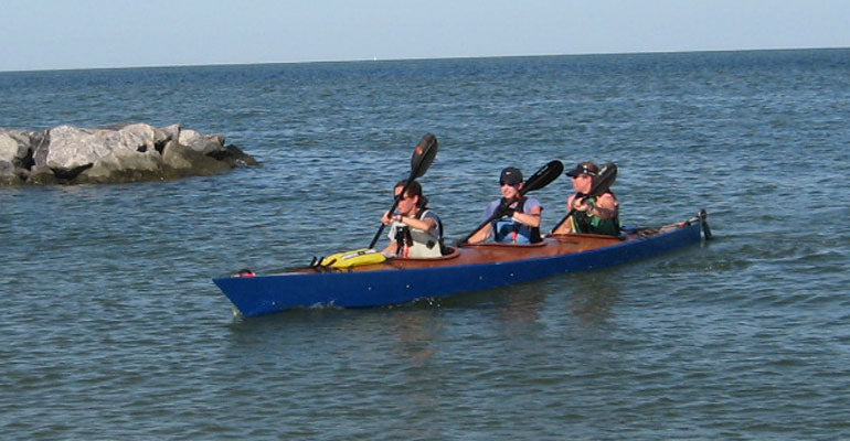 A trio of paddlers heading for shore in a Chesapeake Triple wooden kayak built by Jason R.