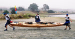 Three paddlers carrying a Chesapeake Triple wooden kayak ashore after a race. Built by Mark M. Thumbnail