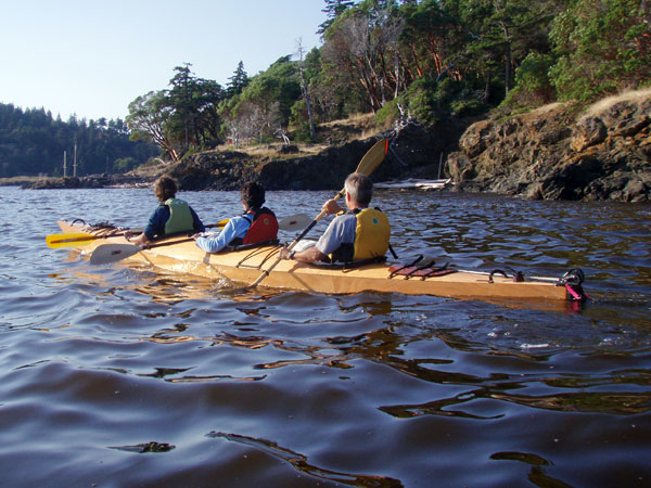 A trio of paddlers in a Chesapeake Triple wooden kayak built by Jonathan M.