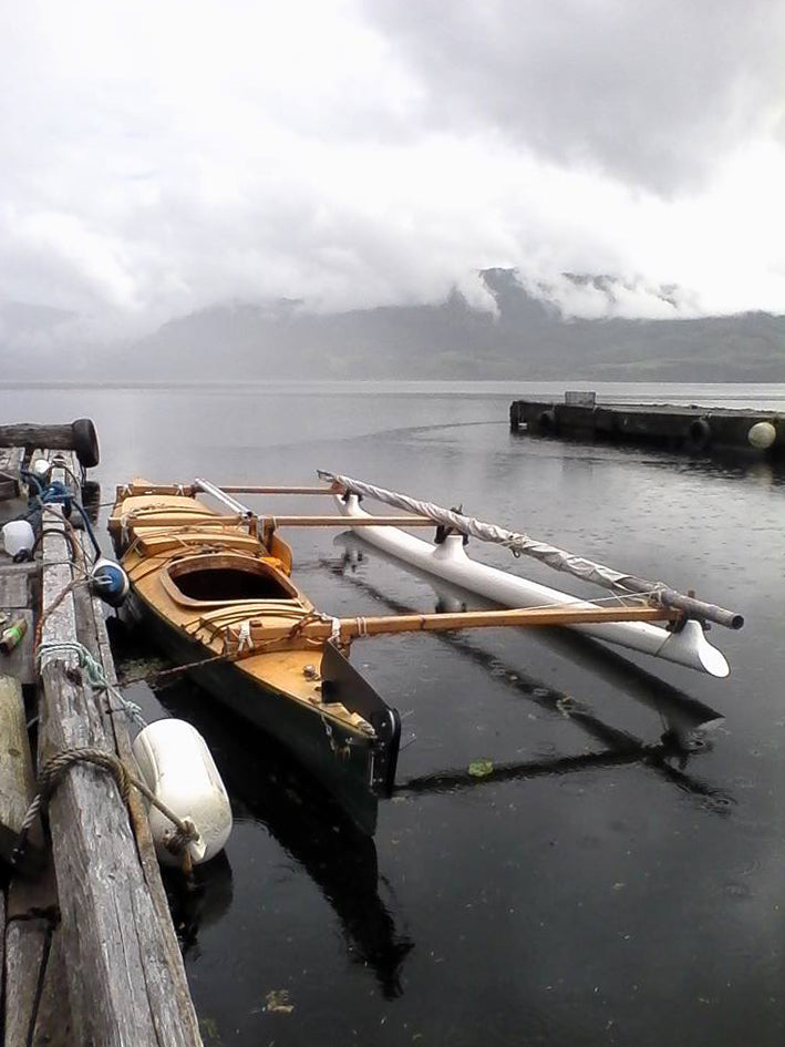A Chesapeake Triple wooden kayak built by David B. with an outrigger and sailing rig.
