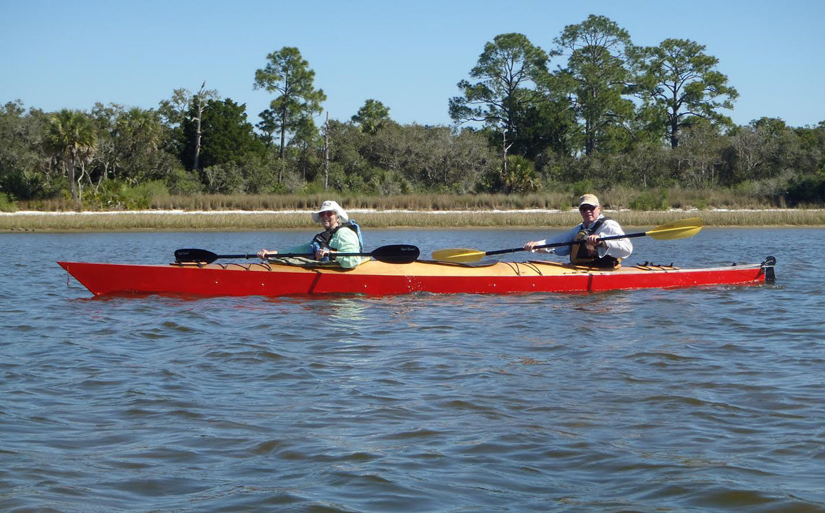 A couple paddling a red-hulled Chesapeake Triple wooden kayak built by David M.