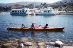 With dogs riding in the forward and aft cockpits, a man paddles a Chesapeake Triple wooden kayak built by Gerry O. on Okanagan Lake, British Columbia Thumbnail
