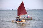 A trio of paddlers in a Chesapeake Triple wooden kayak passing a Skerry Day Sailer at OkoumeFest 2016 Thumbnail
