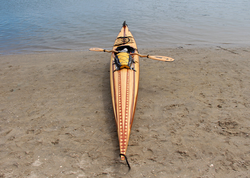 A creatively strip planked Guillemot Single wooden kayak on the shore at Newport Beach, CA