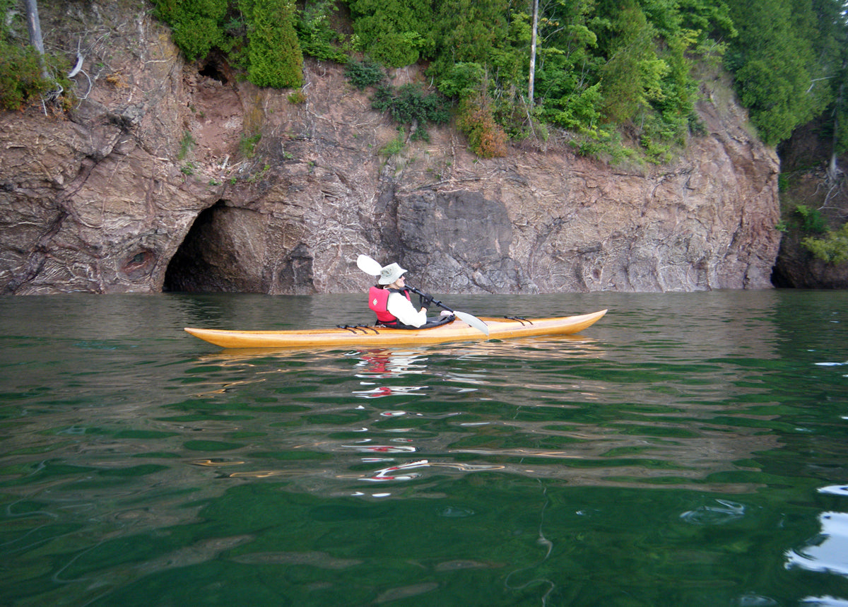 A woman paddling a Guillemot single wooden kayak built by Jim S. at Pictured Rocks National Seashore