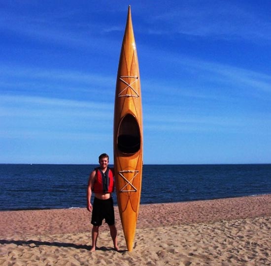 Christopher M. with his Guillemot Single wooden kayak at the beach