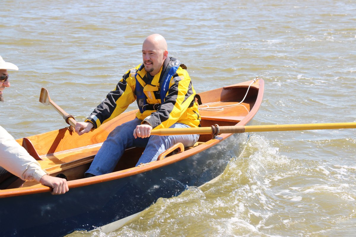 Two men rowing a CLC Jimmy Skiff from the front rowing station.  
