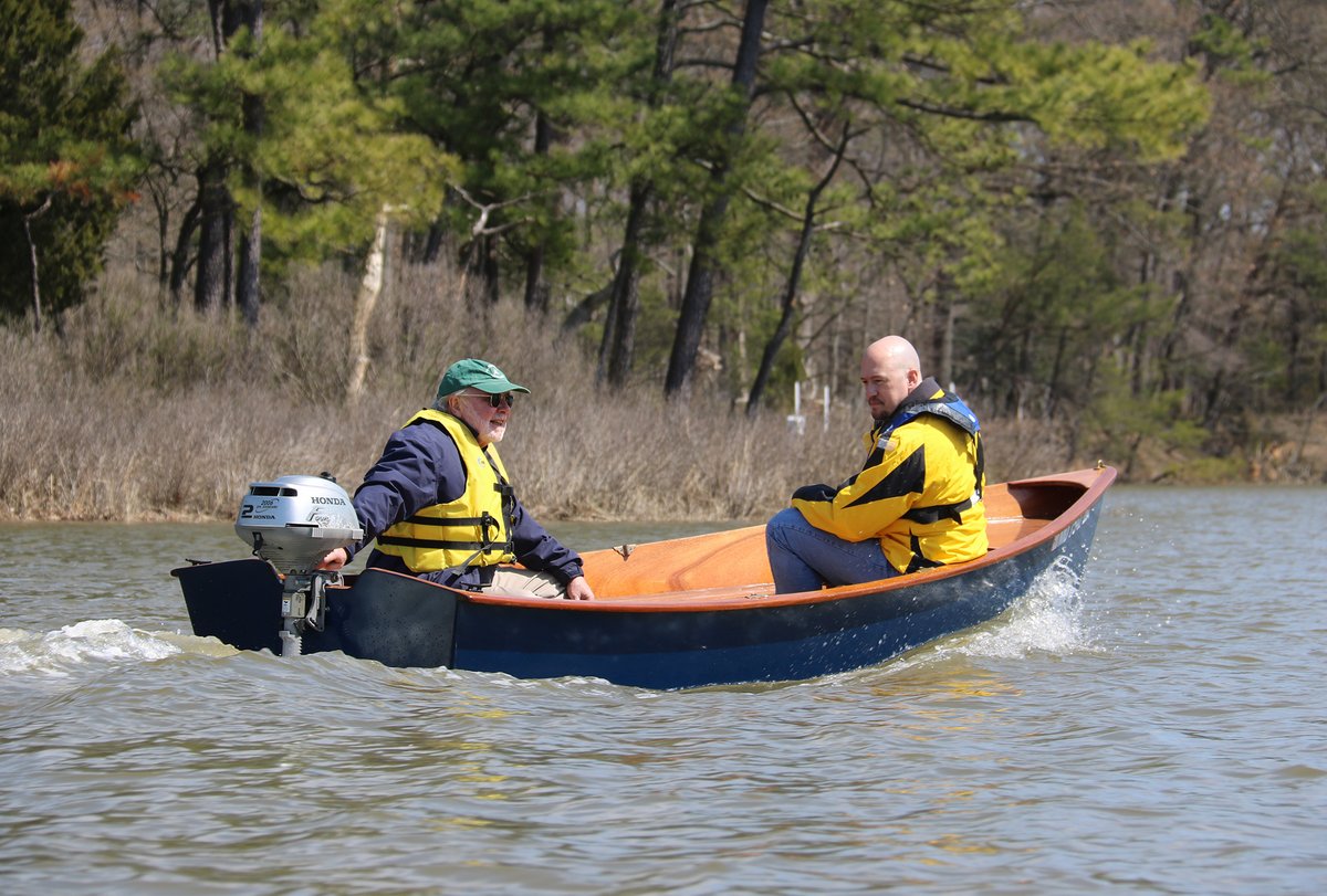 Jimmy Skiff with 2 men motoring with a 2hp Honda outboard. 