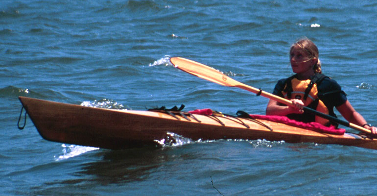 A woman paddling a Chesapeake 16LT wooden kayak