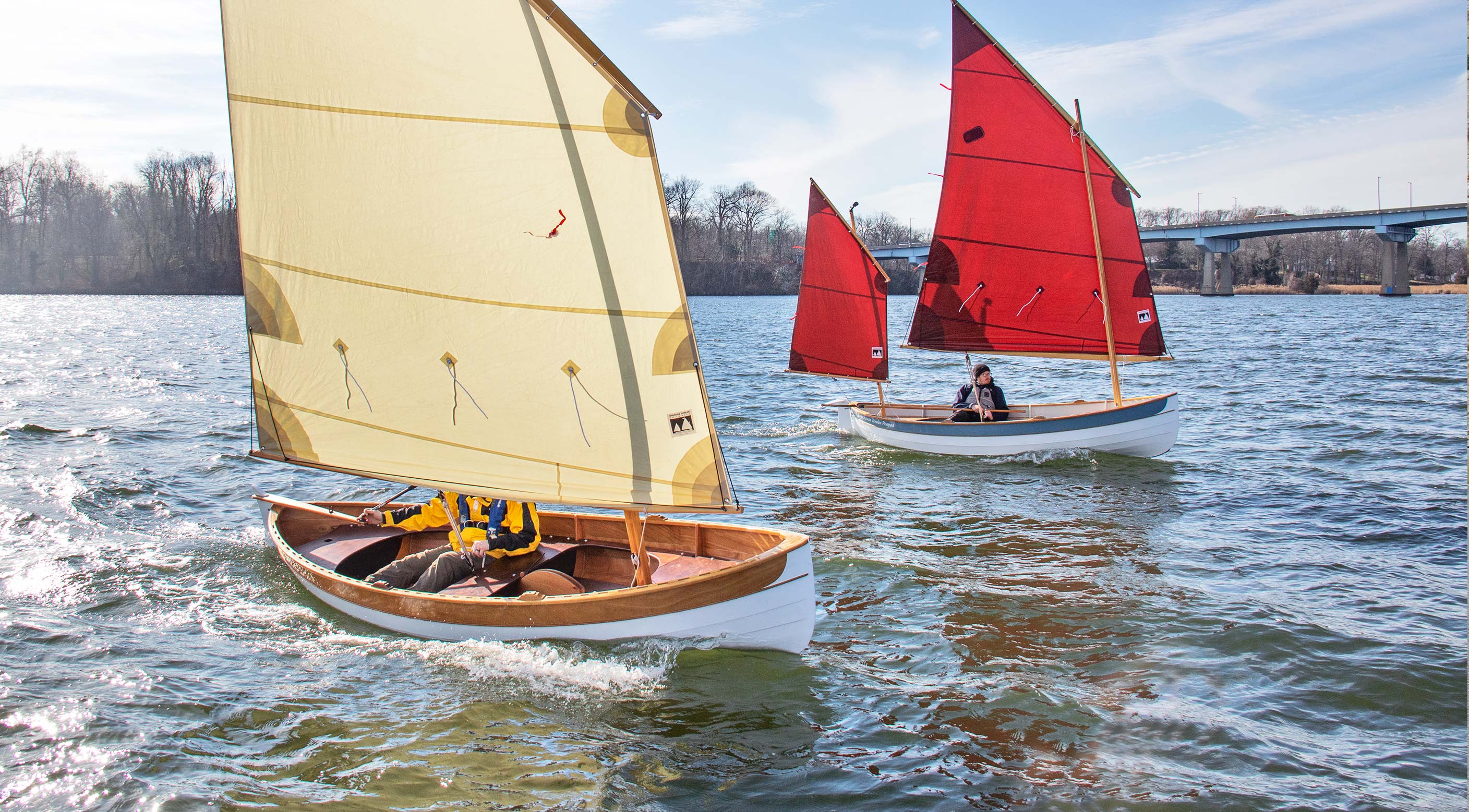 Two wooden sailboats on a body of water with clear skies