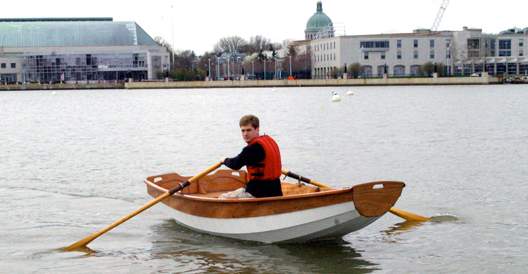 Passagemaker Dinghy rowing in Annapolis Harbor with the US Naval Academy in the background.