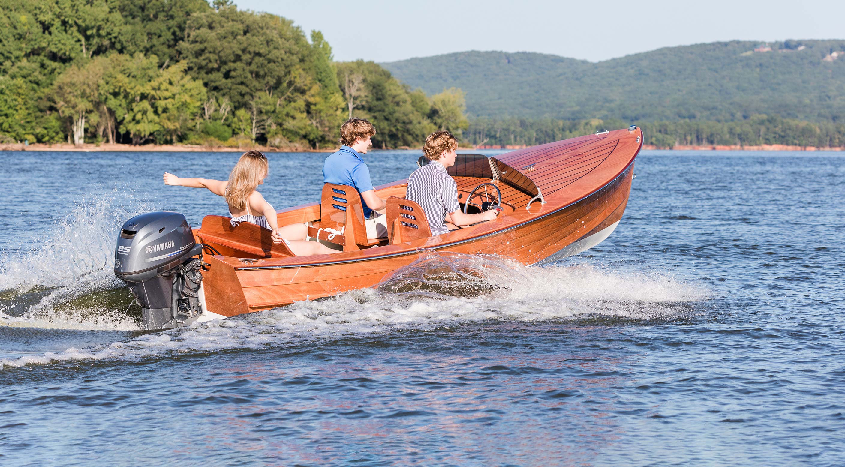 Wooden boat with people on a lake with mountains in the background