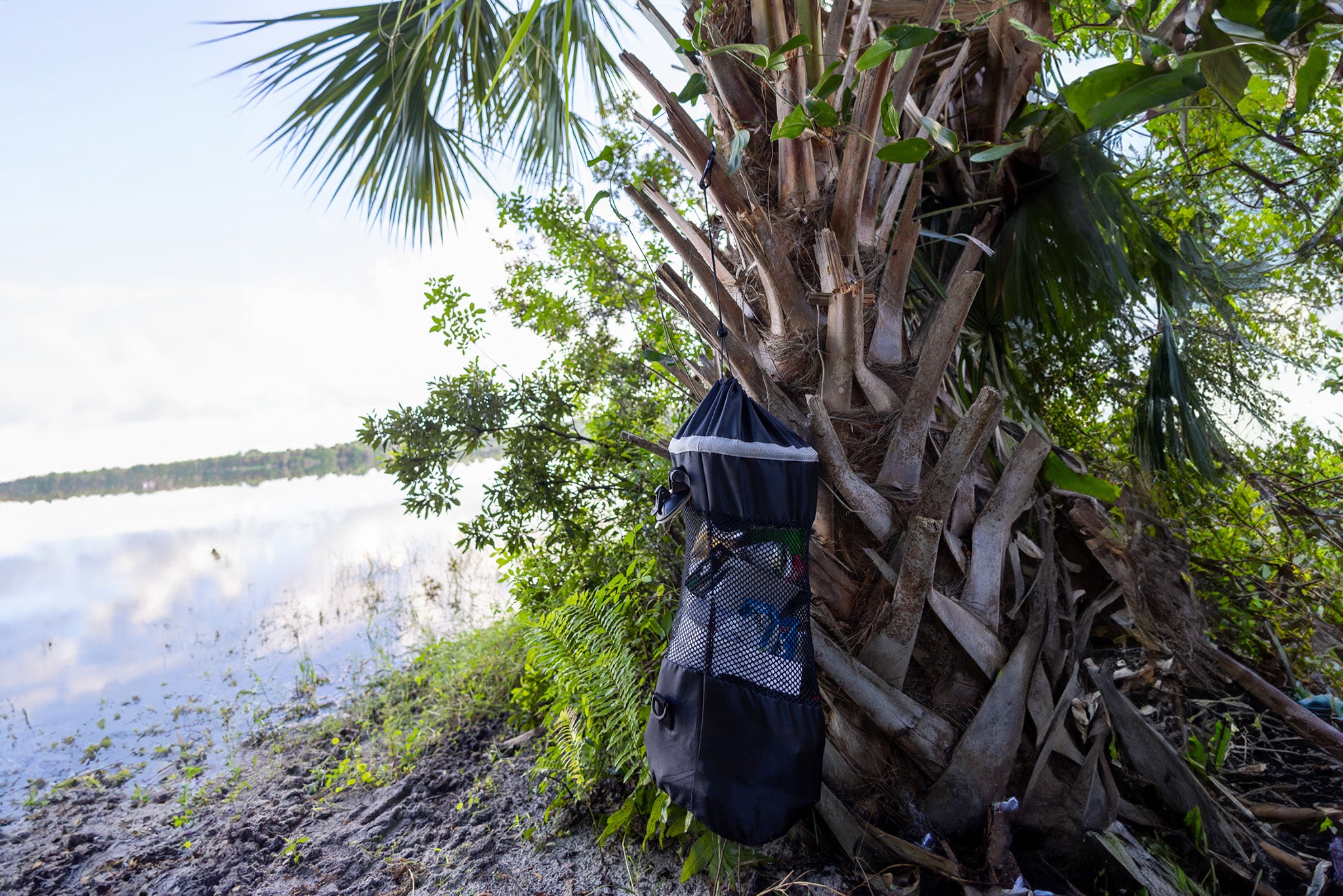 mesh trash bag hung from palm tree