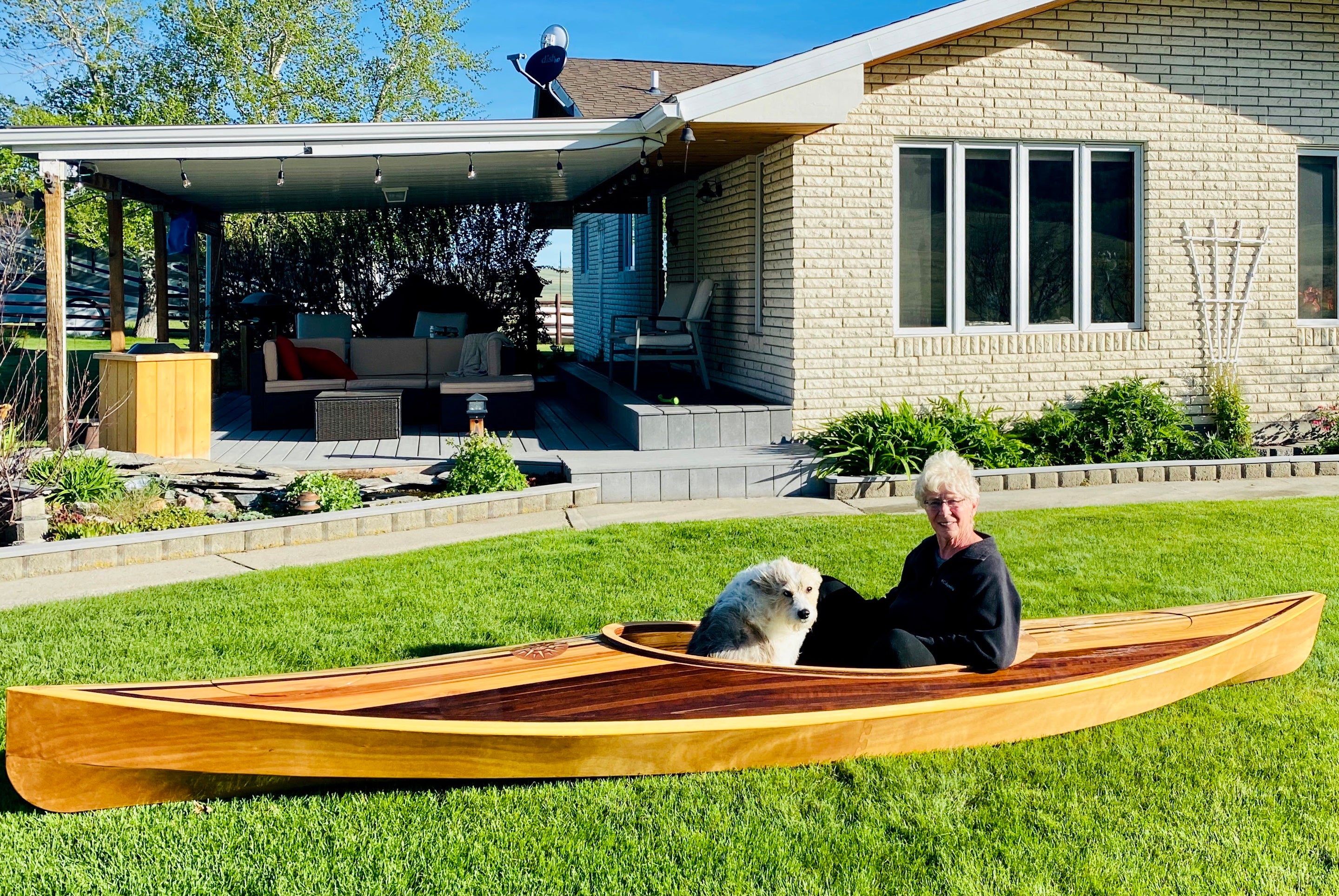 Builder Dave L's wife and dog trying out the fit of his Wood Duck 14 Hybrid kayak on their lawn.