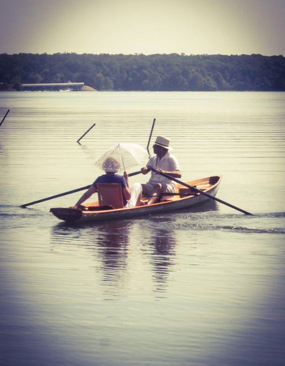 A man rowing a passenger with a parasol in an Annapolis Wherry built by Ronald L.