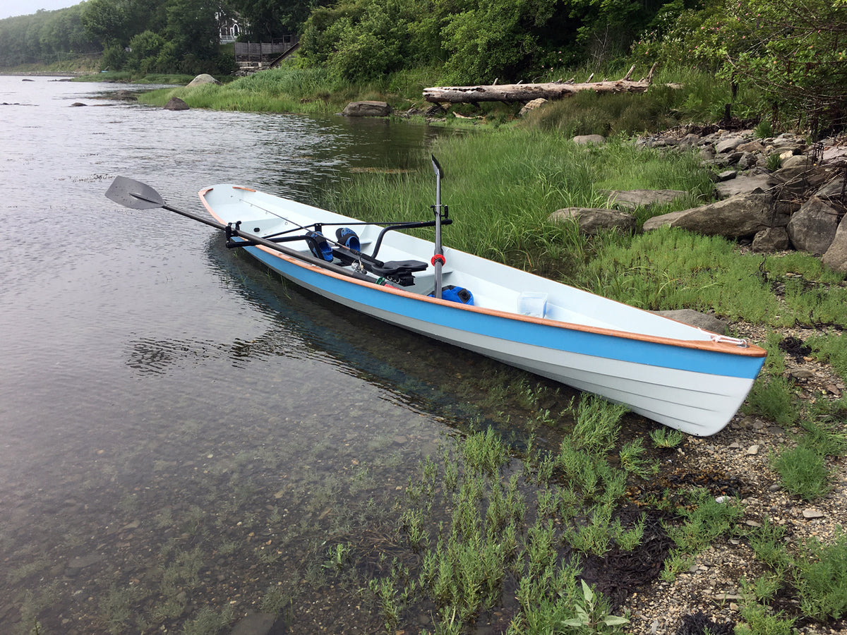 A blue and white Annapolis Wherry built by Ronald G., resting on the shore