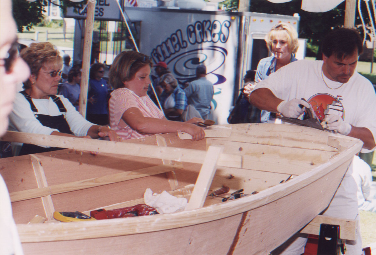 A family at work on their Bevin's Skiff wooden boat kit at a family boatbuilding event