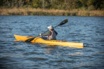 A woman paddling a Chesapeake 16LT wooden kayak along a marshy shore Thumbnail
