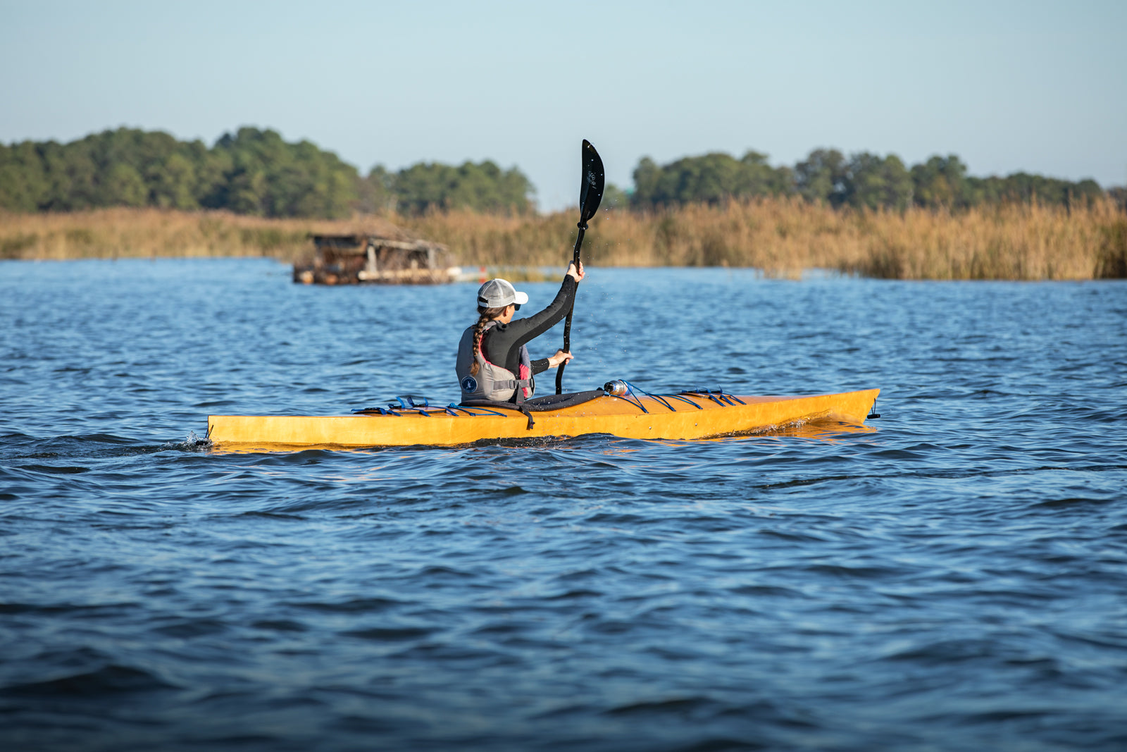 A woman paddling a Chesapeake 16LT toward a marsh