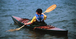 A boy paddling a Chesapeake 14 wooden kayak Thumbnail