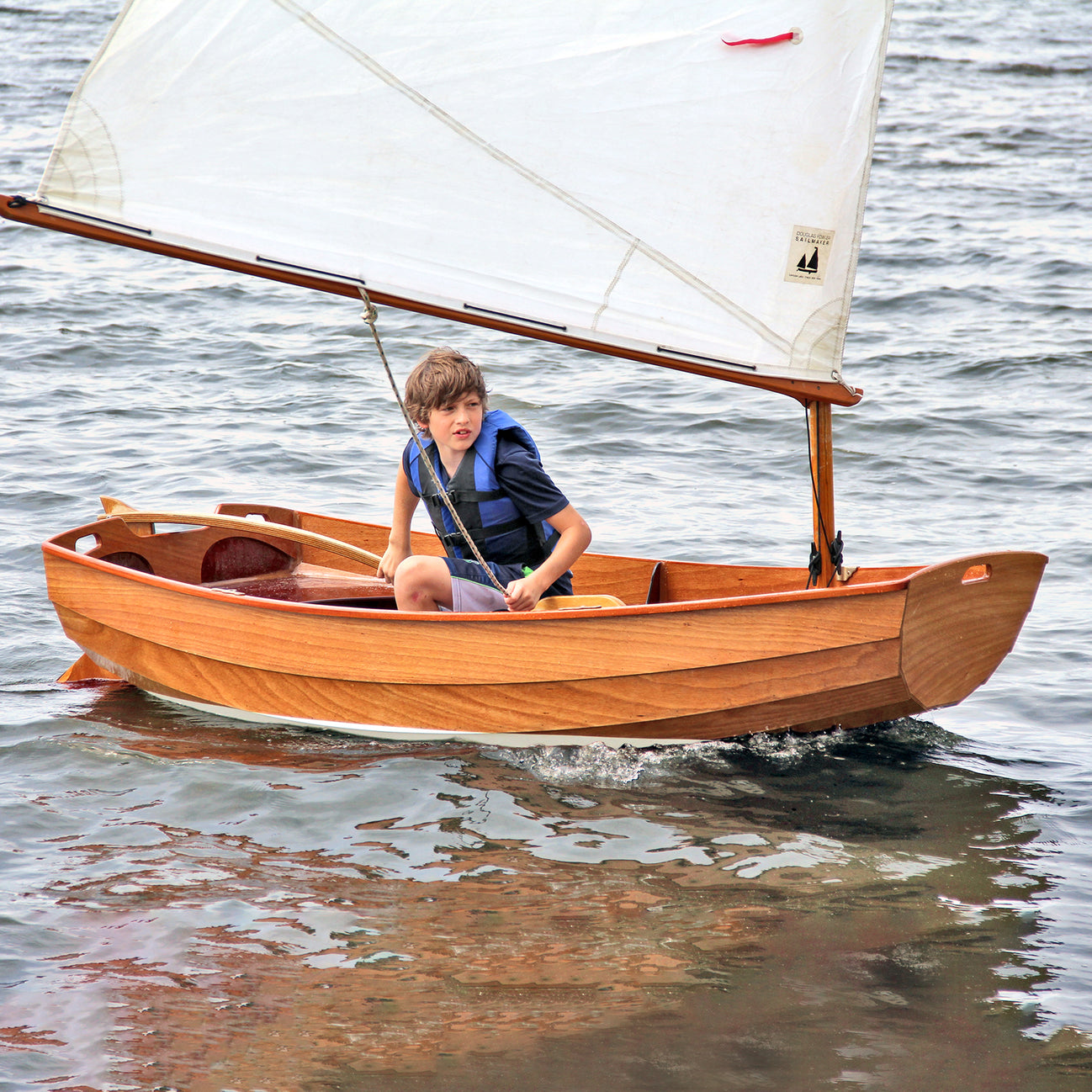 A young sailor looks eagerly ahead for the helm of his Eastport Pram.