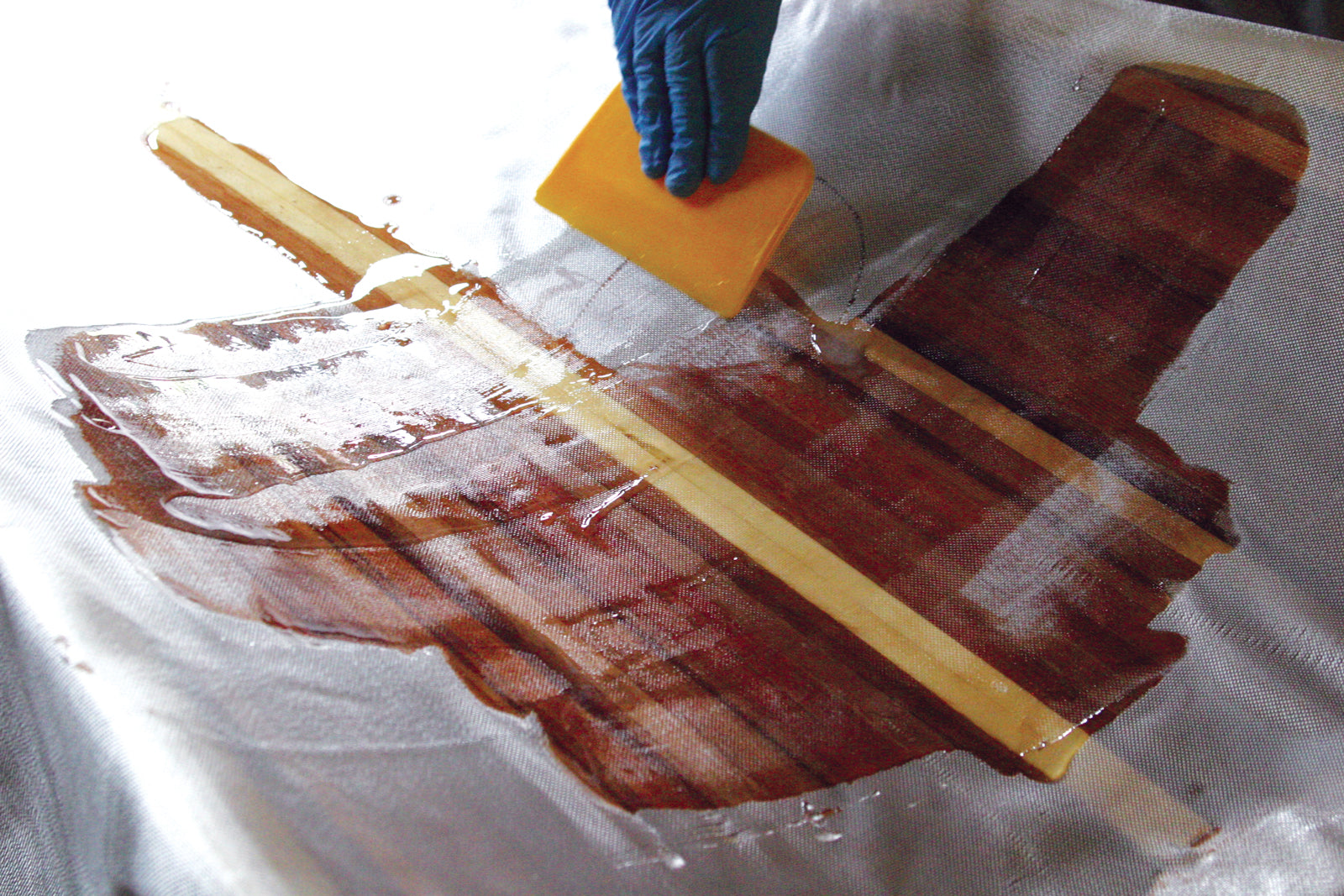 Plastic epoxy spreader being used on fiberglass.