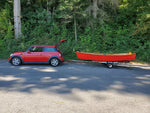 Red Jimmy Skiff hull on a trailer behind a red Mini.  Thumbnail
