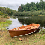 Customer built Jimmy Skiff on a lake shoreline. Varnished interior and exterior, with a white bottom. Thumbnail