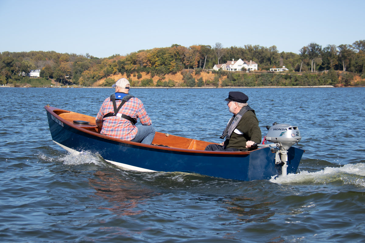Jimmy Skiff with two men motoring using a 2-hp Honda outboard. 