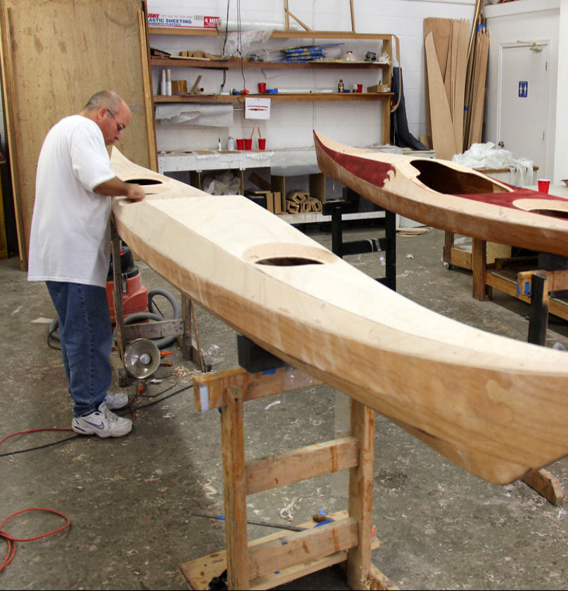 Student building a Petrel SG kayak  in a class led by designer Nick Schade. A Petrel Play SG is on the right.